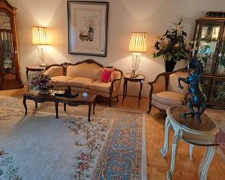 Part of living room with French inspired sofa and chair, large grandfather clock, side tables and crystal lamps