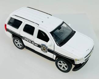 This lot includes the Welly Diecast Police SUV No. 43607, a 1:64 scale model of the 2008 Chevrolet Tahoe Police Vehicle in white, featuring classic pull-back action. 