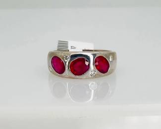 14K white gold ruby and diamond ring, size 6.25. (3) oval cut rubies, weighing 1.9 ctw, and (4) round cut diamonds, weighing 0.09 ctw, are set in the center of the band. 5.1 gtw. Includes appraisal dated September 18, 2024 by American International Gemological Laboratories, Inc. Appraisal provided by consigner. 