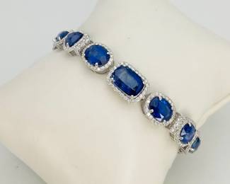 Oscar Friedman 7" platinum bracelet mounted with (15) genuine sapphires weighing approximately 31.77 ctw and (332) round diamonds, weighing approximately 3.3 ctw. Finished with a tension lock clasp and folding safety clasp. 24.2 gtw. Includes appraisal dated August 27, 2025 by American International Gemological Laboratories Inc. Appraisal provided by consigner. 