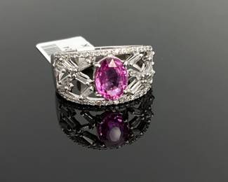 14K White Gold size 7.25 ring with a 1.6 ct oval cut pink sapphire at the center. Center stone is approximately 8.27 mm x 6.3 mm. (14) baguette and (42) round cut diamonds accent the center stone around and on both sides. 4.6 gtw. Includes appraisal dated April 18, 2025 by GemAssure Gemological Appraisals. Appraisal provided by consigner.