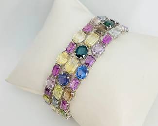 Triple strand platinum bracelet set with (70) multi colored sapphires of various shapes and sizes, 67.84 ctw. Bracelet is stamped "Oscar Friedman" and finished with a double tension locking hook clasp. 52 gtw. Includes appraisal dated August 14, 2024 by American International Gemological Laboratories, Inc. Appraisal provided by consigner.