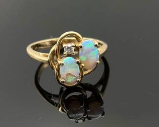 Size 5 14K gold ring mounted with (2) oval cut opals and (1) diamond. (1) opal is chipped. 2.69 gtw.