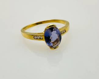 An oval cut amethyst is set at the center of this size 7.5 gold ring. (3) diamonds line the band on either side of the center stone. Stamped "10K".