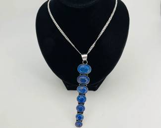 3" lapis lazuli pendant made of (7) lapis cabochons in descending size, set in unmarked silver tone. Hangs from a sterling silver, stamped 925, 15" chain. 23.9 gtw.