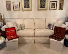 Couch, artwork, small ottomans and gold silverware 