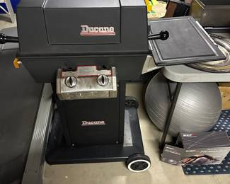 Ducane BBQ grill shown open with side table that tucks inside when closed and fitness ball with box