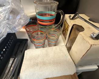 Keurig in back, set with pitcher with matching glasses, knife set to left