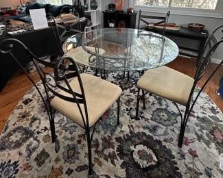 Glass-top round table with 4 wrought iron chairs.