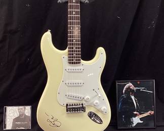 ERIC CLAPTON AUTOGRAPHED FENDER 6 STRING ELECTRIC GUITAR WITH CERTIFICATE OF AUTHENTICITY FROM AUTOGRAPH STORE NY, NY. ORIGINALLY FEATURED IN A BENEFIT AUCTION AT CHAPEL HILL 2014. INCLUDES FRAMED TIME PIECES VINYL ALBUM, BEST OF EC CD AND FRAMED PHOTO