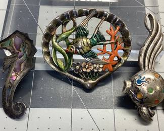 3 VTG STERLING OCEANIC BROOCHES MEXICO STERLING SEA HORSE INLAID WITH ABALONE 2.25 INCHES TALL, FISH WITH ENAMEL SIGNED M 2.5 INCHES TALL, FISH IN CLAM SHELL WITH ENAMEL. TOTAL WEIGHT 41.61 GRAMS. PATINA WAS LEFT TO PRESERVE PIECES.
