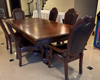 45x90 inch wooden dining table. (2) 15 inch sleeves can be taken out to make it smaller. Includes 6 wooden & leather chairs with ornate detailing. 2 arm chairs & 4 armless chairs. 