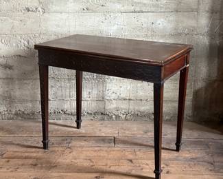 This lot features an antique George III solid mahogany game table. This table is in good overall condition, but does have one loose leg shown in photos. This table measures closed, 29” H x 19” W x 36” D and open, 29” H x 38” W x 36” D.
