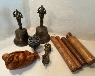 Collection of Tibetan Buddhist ritual implements, including bells, vajra, incense burner, Buddha carving
