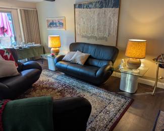 Living room area - black faux leather couch, loveseat and chair. Glass top side tables. MCM lamps!
