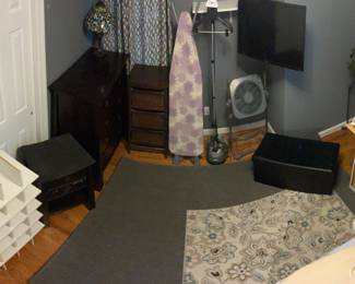 Shoe rack for the closet -end table with/drawer-a set of three drawers-ironing board-steam machine-a fan-Toshiba TV -storage -shoe rack, plus the rugs on the floor.