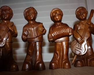 Hand carved wood minstrels :  one w/small guitar/one w/song book/one w/accordion/and one w/bass guitar 