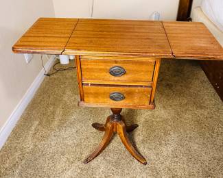 This is an antique Duncan Phyfe-style mahogany drop-leaf table with two drawers and a pedestal base.