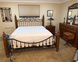 This is an Ashley Wyatt Queen Poster Bed with a medium brown cherry finish and antique bronze-toned scrolling metalwork.