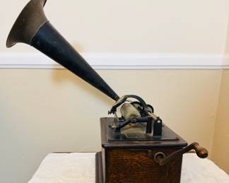 Antique Edison cylinder phonograph The phonograph features a large external horn, a hand crank, and a wooden base, likely made of oak. With records