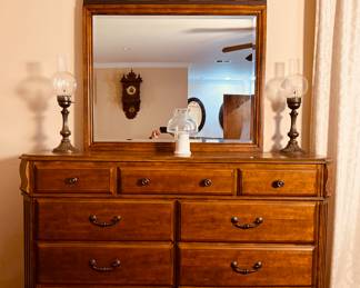 This is an Ashley Furniture Wyatt 9-drawer dresser in a medium brown cherry finish with an ornate metal-arch mirror.