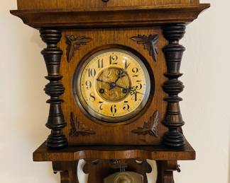 This is an antique German Junghans or Gustav Becker Victorian walnut wall clock with a mechanical pendulum movement and decorative carvings.
