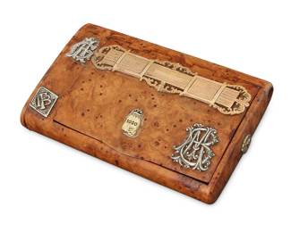 162
A Russian Karelian Birch & Mixed Metal Cigarette Case
Featuring a burl-patterned Karelian birch case with hinged lid and multiple applied mixed metal monogram crests and coins, including sterling silver, 10K and 18K gold plate, with a strike plate to one end

Measures: 4 1/4 x 2 3/4 x 3/4 in.
54.4 grams gross
Estimate: $1,000 - $1,500