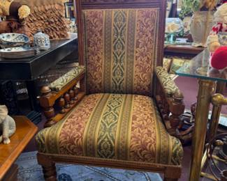 Victorian-style carved oak framed library reading armchair with turned lets and upholstered in a patterned damask fabric.