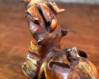 This lot features a beautiful ochre, copper, and viridescent example of a Chinese Pixiu. The creature is depicted with mouth agape, and standing in a fighting stance, his tail twitches behind him frozen in time. Pixiu is a Chinese mythical hybrid creature. Pixiu are considered powerful protectors of the souls of the dead, and resemble strong, winged lions. This sculpture of a Pixiu measures, 7” H x 3” W x 9” D.

