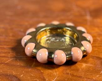 This lot features a Fisher Jewel Tray commemorating the 1939 New York World’s Fair. The tray is made of hammered brass with a ring of coral-colored vitro agate marbles around the outer circumference. These small trays were originally designed to hold ladies’ jewelry. 
