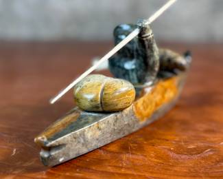 "Hunter and Kayak", an Inuit hand-carved sculpture, likely made of soapstone by listed artist, Arnold Kayutak. Signed underneath as shown in photos and measures, 4” H x 9.5” W x 4” D.
