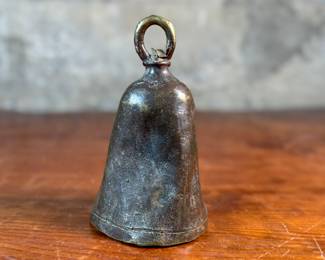 This lot features an antique African brass cattle bell that measures, 7” H x 4” W x 4” D.
