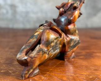 This lot features a beautiful ochre, copper, and viridescent example of a Chinese Pixiu. The creature is depicted with mouth agape, and standing in a fighting stance, his tail twitches behind him frozen in time. Pixiu is a Chinese mythical hybrid creature. Pixiu are considered powerful protectors of the souls of the dead, and resemble strong, winged lions. This sculpture of a Pixiu measures, 7” H x 3” W x 9” D.
