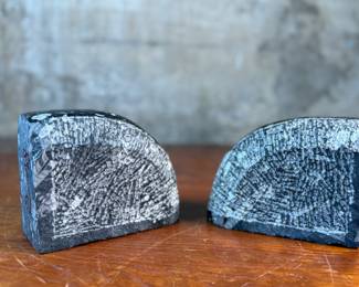 This lot features a pair of polished black marble Orthoceras fossil bookends. Each one measures, 4.5” H x 6” W x 3” D.
