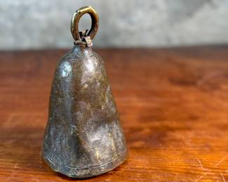 This lot features an antique African brass cattle bell that measures, 7” H x 4” W x 4” D.
