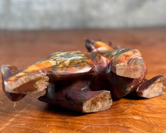 This lot features a beautiful ochre, copper, and viridescent example of a Chinese Pixiu. The creature is depicted with mouth agape, and standing in a fighting stance, his tail twitches behind him frozen in time. Pixiu is a Chinese mythical hybrid creature. Pixiu are considered powerful protectors of the souls of the dead, and resemble strong, winged lions. This sculpture of a Pixiu measures, 7” H x 3” W x 9” D.
