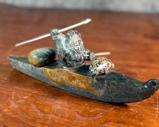 "Hunter and Kayak", an Inuit hand-carved sculpture, likely made of soapstone by listed artist, Arnold Kayutak. Signed underneath as shown in photos and measures, 4” H x 9.5” W x 4” D.

