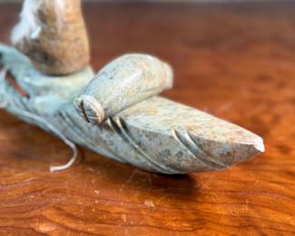 This lot features a hand-carved soapstone sculpture of an Inuit hunter and kayak. Signed underneath and measures, 6” H x 15” W x 3” D. The hunter has come detached as shown in photos and can sit just fine or be reattached.
