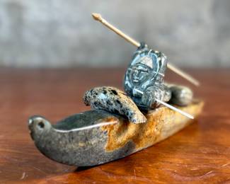 "Hunter and Kayak", an Inuit hand-carved sculpture, likely made of soapstone by listed artist, Arnold Kayutak. Signed underneath as shown in photos and measures, 4” H x 9.5” W x 4” D.
