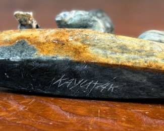"Hunter and Kayak", an Inuit hand-carved sculpture, likely made of soapstone by listed artist, Arnold Kayutak. Signed underneath as shown in photos and measures, 4” H x 9.5” W x 4” D.
