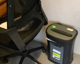 Desk chair and shredder in sunroom.