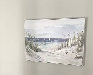 Beautiful beach picture on wall in frame.