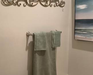 A beautiful wall hanging in the bathroom, with beautiful towels and ocean canvas.