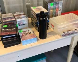 White small farm table in sunroom. Has C.D’s and movies on it. It measures: 53” length, 23 3/4” width, 31 1/4 “ tall. Price is $85.00.