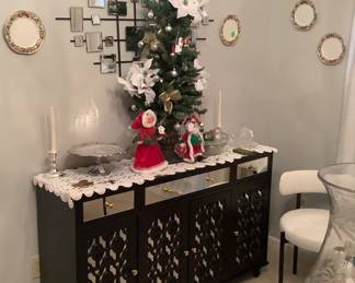 The beautiful black modern buffet with glass top, and mirrored front. The modern wall mirror is behind it with Waterford saucers hanging on wall. Price: $475.00 It was made by FuFu, GA, GA. Mirror behind buffet is: $95.00.