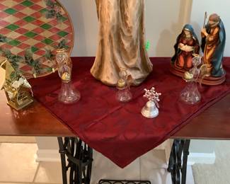 Sewing machine base with wood top to display Mary and Joseph with Baby Jesus and Angel watching.