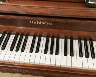Close-up of the Baldwin. Beautiful wood. Measures 56” width, 26 1/2” depth, 44” height. Price is: $1,400.00. It also comes with the bench loaded with music sheets.