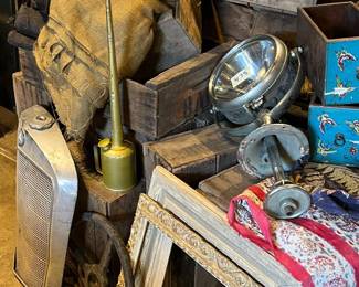 Industrial and Americana-style grouping featuring weathered wooden crates, vintage metal gauges, automotive or machinery parts, framed decorative elements, and assorted workshop accessories. Rich patina and layered textures throughout create a strong rustic, industrial aesthetic. Ideal for collectors, decorators, or retail and set display. All items sold as-is.