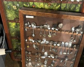 Glass-front display case featuring a curated collection of vintage souvenir and collectible spoons. Includes a wide variety of decorative designs and destinations, neatly arranged for display. Classic nostalgic appeal with light wear consistent with age. Ideal for collectors or themed décor. All items sold as-is.
