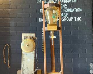 Unique industrial-era scientific or mechanical display featuring two mounted glass bulb apparatuses on wooden and metal stands. Showcases early electrical or laboratory-style components with visible wiring, glass elements, and heavy patina. Striking sculptural presence ideal for collectors, industrial décor, or theatrical and retail display. Condition reflects age; functionality untested. All items sold as-is.